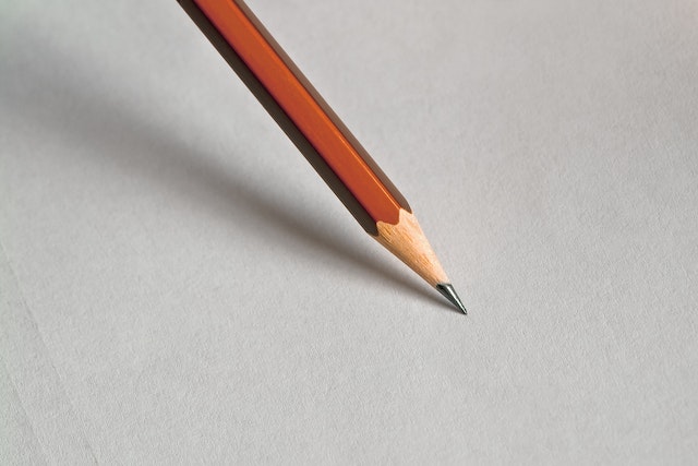 The point of a sharpened pencil is ready to start marking on a blank white sheet.