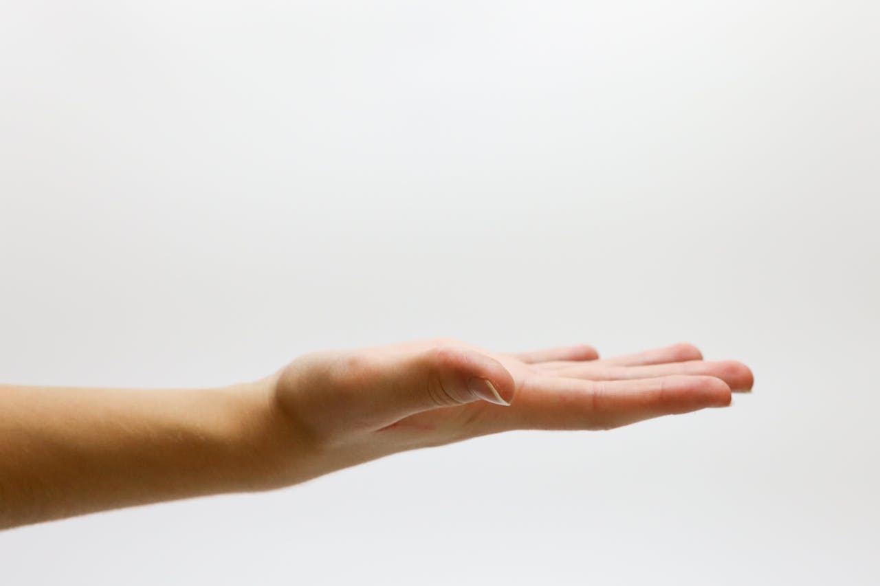 Close up photo of a hand stretched out with palm facing up in a gesture of assistance or help.