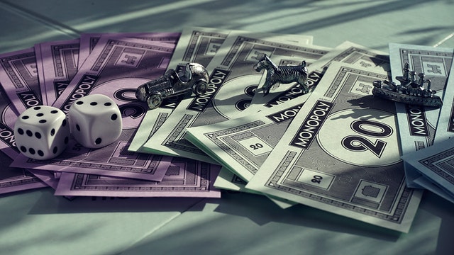Money, dice, and game pieces for Monopoly set spread out on a table.